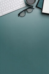 Overhead view of designer workplace with keyboard, glasses, notebook a copy space on dark blue...
