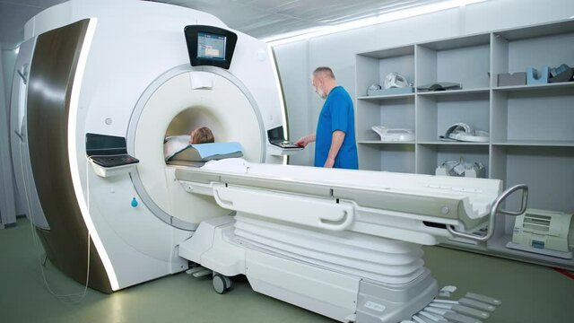 Magnetic resonance imaging in the modern hospital, adult man doctor performs a magnetic tomographic examination of a young woman, MRI, modern technologies in medicine.