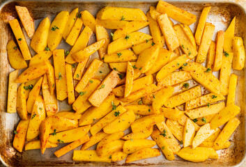 Sliced raw potatoes with spices and herbs on the pan ready for cooking. Selective focus. Shallow depth of field.