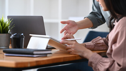 Cropped shot of two businesswoman analyzing business data on digital tablet and sharing ideas in meeting room.