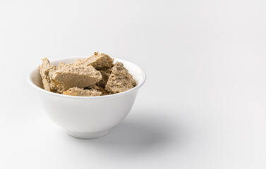 Small pieces of halva in a cup on a light background. Side view with copy space.