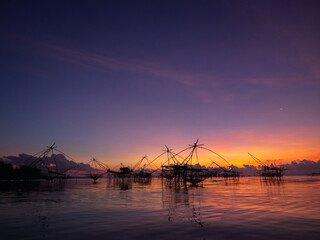 Fototapeta na wymiar Silhouette photo of fisherman trap fish in front of sunrise scene at famous Pak Pra Phatthalung provience Thailand