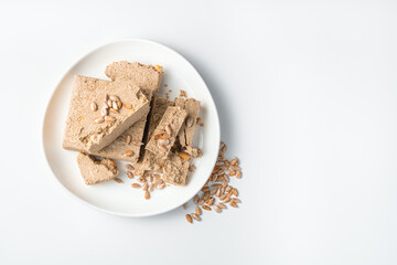 Oriental halva with peanuts on a white plate.
