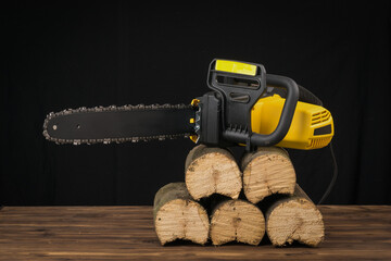 Electric chain saw on sawn wooden logs.