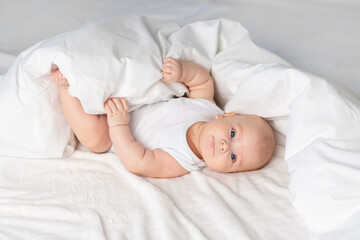 Fototapeta na wymiar happy baby on the bed in the morning. Textiles and bed linen for children. A newborn baby has woken up or is going to bed