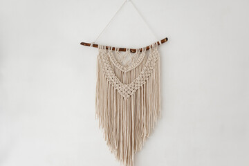 Handmade 100 cotton macrame wall decor hanging on a white wall. © Andrii Lysenko