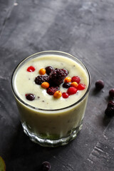 Yogurt with berry and kiwi in a glass. Fruit and berry smoothie. Milkshake with kiwi, raspberry, blueberry and banana Healthy food. Dark background. Copy space.