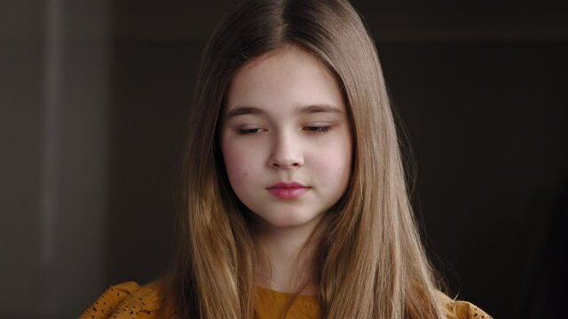 Portrait of sad lonely upset caucasian student schoolgirl standing alone in room looking down feeling stressed of problems. Close-up worried female face, one teen girl daughter thinking about trouble