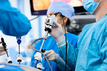 Selective focus on the hand of a surgeon wearing a sterile latex glove holding a special medical instrument during laparoscopic surgery. Minimally invasive surgical treatment of proctological diseases