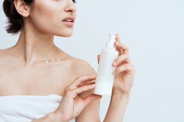 Pretty brunette with bare shoulders lotion in hands skin care close-up