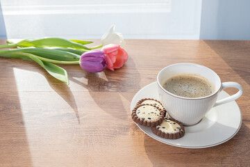 Cup with coffee, cookies and tulips by the window Concept, spring is coming, congratulations on the spring holidays