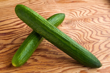 two green cucumbers on the wooden surface of the table