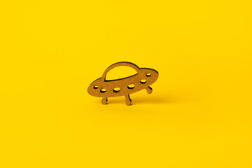 wooden symbol UFO over yellow background
