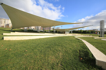front view, empty activity and parking space with grass floor. Large horizontal awnings protecting...