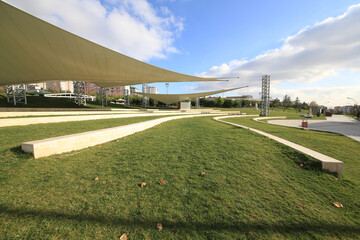 front view, empty activity and parking space with grass floor. Large horizontal awnings protecting...