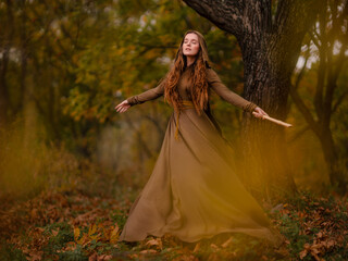 Redhead woman in dress walking in fantasy fairy tale forest