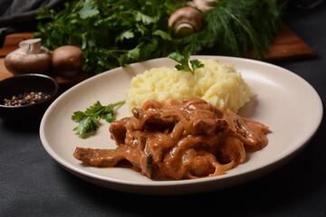 Traditional beef stroganoff in a ceramic white plate with mashed potatoes