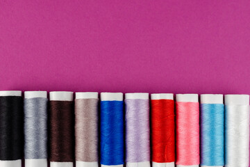 Multicolored Reels of Thread on a Purple Background.