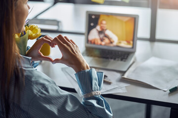 Dark-haired female office employee demonstrating love for her boyfriend