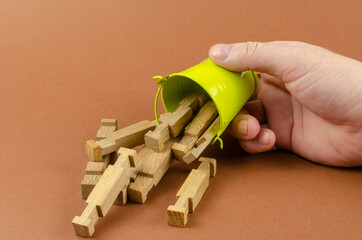 Small bucket, wooden puzzles and a hand on a brown background.