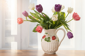 A bouquet of beautiful, delicate tulips in a vase on the window. Concept, spring is coming, congratulations on spring holidays