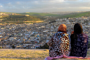 Two Moroccan women looking high above the city of Fez
