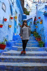 Young girl posing in the blue streets of Chaouen in Morocco