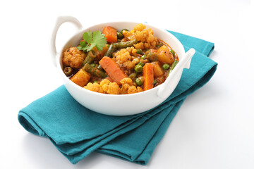 MIX VEGETABLE CURRY- indian recipe, mixed veg containing Carrots, cauliflower, green peas and beans with traditional masala and curry, red hot and spicy served in a ceramic bowl

