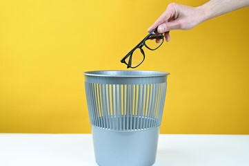 Hand throws glasses into the trash can