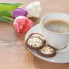 Cup with coffee, cookies and tulips by the window Concept, spring is coming, congratulations on the spring holidays