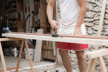 Male carpenter working with wood material in a garage.