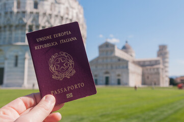 Man hold an italian passport in front of the world famous leaning tower of Pisa