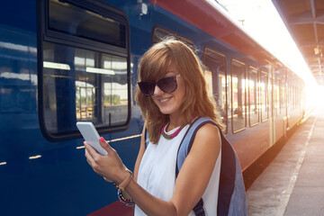 Woman using cellphone on a train station.