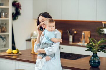 Mom communicating on smartphone with child in arms