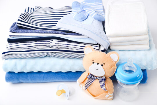 Folded baby clothes with diapers and soft bear toy