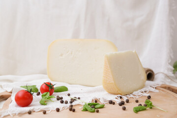 Medium hard cheese head parmesan on wooden board, with cheese parmesan with tomatoes on the table
