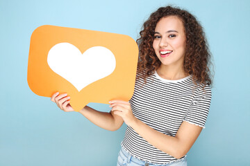 Young american girl holding paper heart on blue background