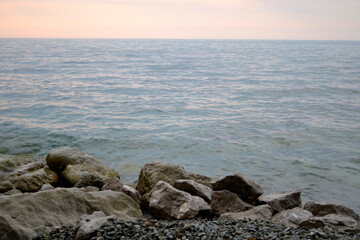 Fototapeta na wymiar gray sea with rocks on the Beach and pink horizon