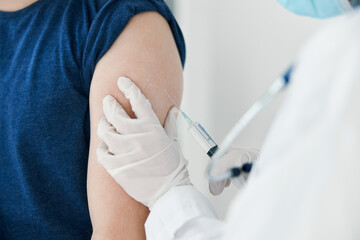 woman doctor in protective gloves injections in the shoulder of a man in a blue t-shirt vaccination
