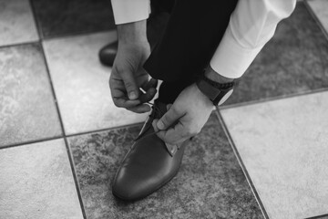 High angle shot of a man tying shoelace in grayscale