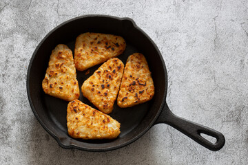 Hash browns cooked in a cast iron frying pan.  Concrete background