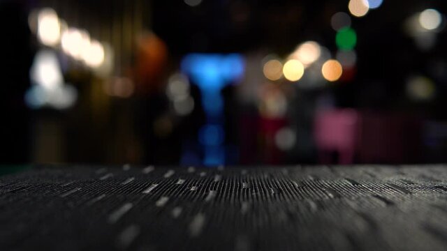 Beautiful interior of the restaurant in dark colors. Blurred background, moving people. In the foreground is a table top as a template or mockup for a video.