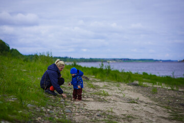 portrait of a boy in a blue jacket with his mother in the open air, river bank, selective focus