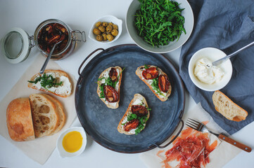 italian traditional bruschetta - bread toast with sun dried tomatoes, cream cheese, olive oil and arugula.