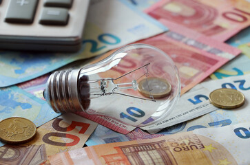 An incandescent light bulb and a waste of money. The concept of abandoning  obsolete technologies. Selective focus.