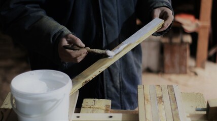 applying glue to a narrow wooden plank in the process of creating a wood product in the atmosphere of a carpentry workshop, carpentry for the production of a panel from narrow boards