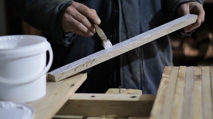 applying glue to a narrow wooden plank in the process of creating a wood product in the atmosphere of a carpentry workshop, carpentry for the production of a panel from narrow boards
