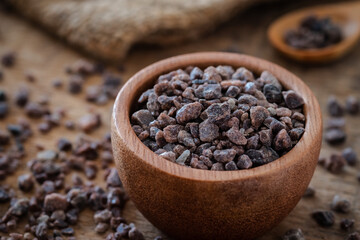 Himalayan black rock salt in wooden bowl.