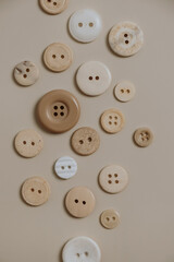 Buttons pattern on neutral beige background. Flat lay, top view. Minimalistic sewing concept.