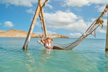 Travel and vacation concept - Woman relaxing on hammock at the sea